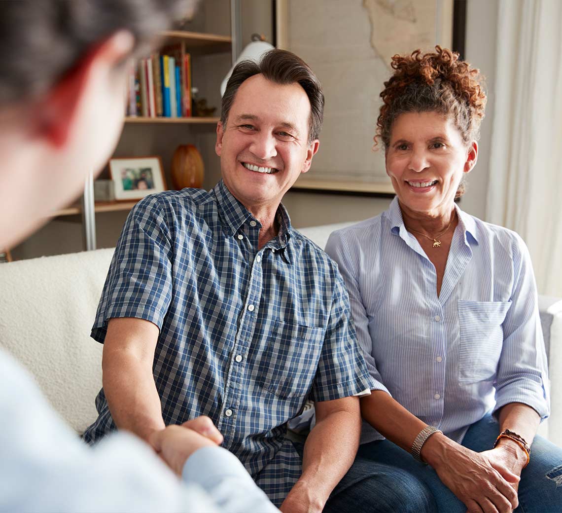 senior man shaking the hand of a finanicial advisor sitting next to his wife discussing keys to a successful retirement