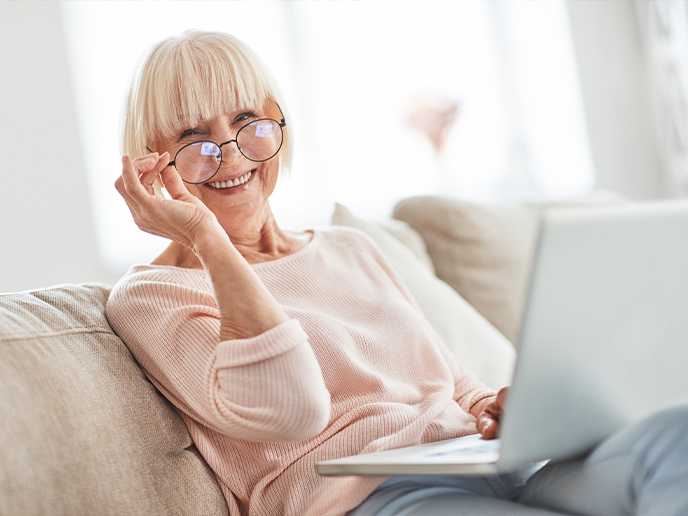 smiling senior woman sitting on the couch with her laptop do annuities work