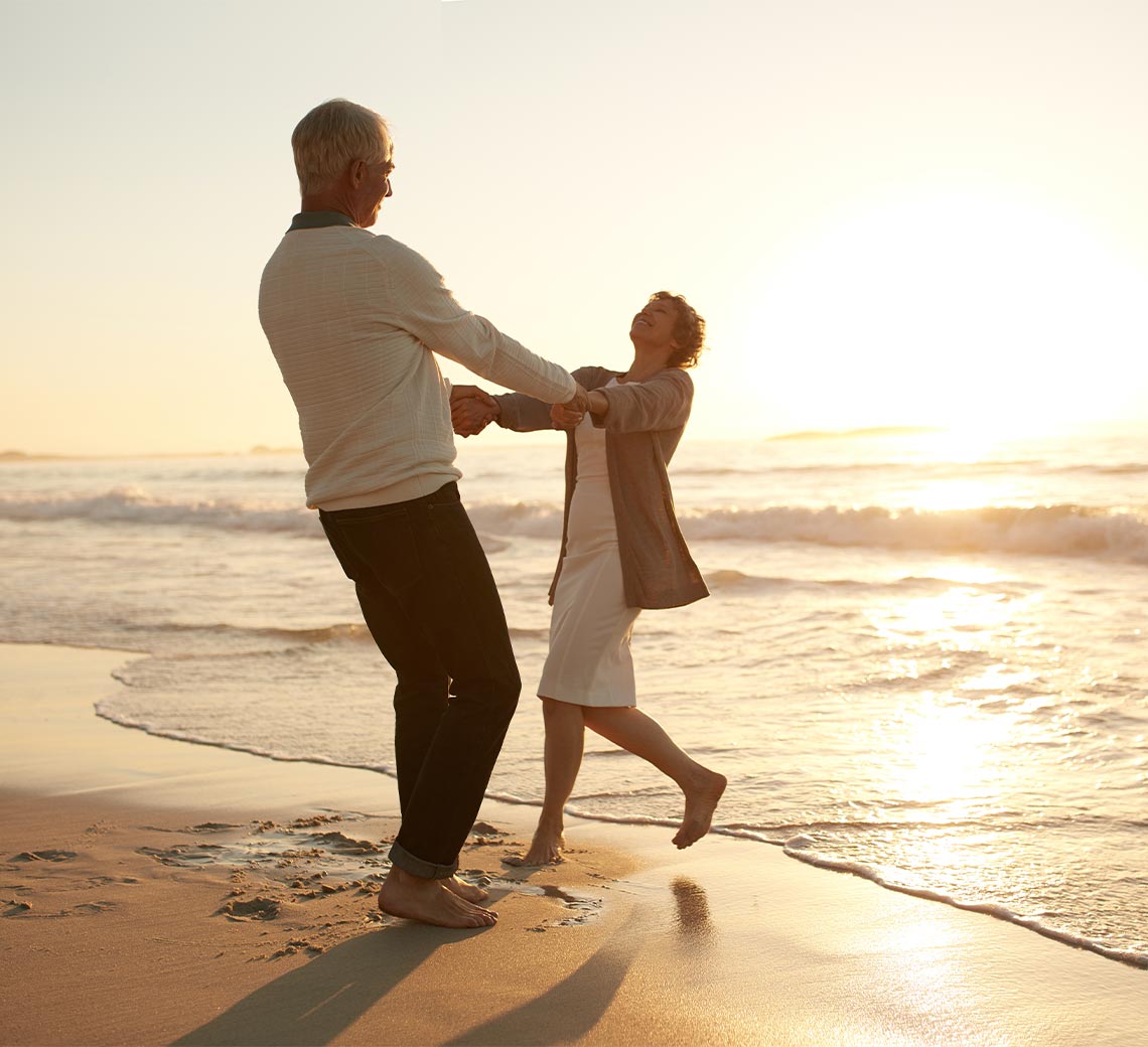 middle aged couple dancing on beach at sunset income for life