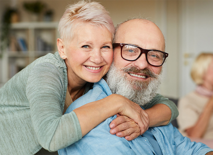 portrait of senior woman with her arms around her husband both with big smiles on their faces life insurance in retirement